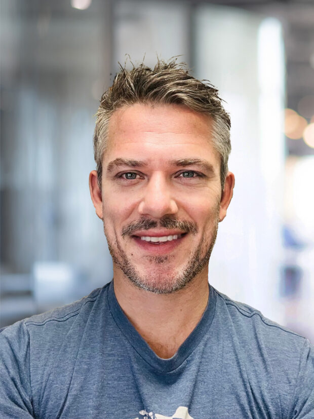 Professional portrait of Luke, digital marketing expert, in front of a blurred office background.